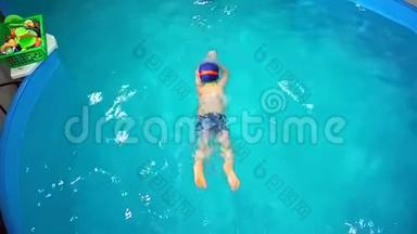 一个小男孩在<strong>游泳池</strong>里学游泳，俯视，他跳进水里。